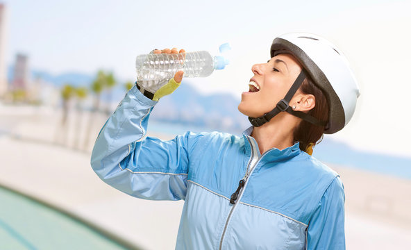 portrait of cyclist middle aged woman drinking water in the beac