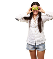 portrait of young girl holding kiwi slices in front of her eyes