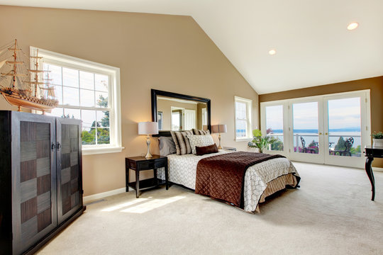 Classic luxury large bedroom with water view and carpet.
