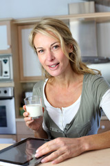 Portrait of blond woman drinking milk in home kitchen