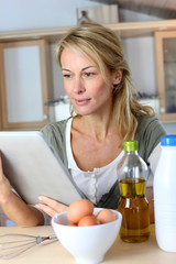 Woman in kitchen looking at dessert recipe on internet