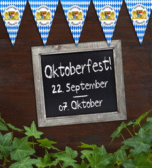 Tafel mit Oktoberfest auf Holzbrett mit Efeu und Wimpeln