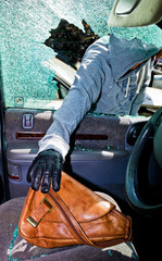 Ein Dieb entwendet eine Handtasche aus Auto