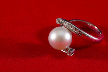 Ring with pearl and diamond on a red background