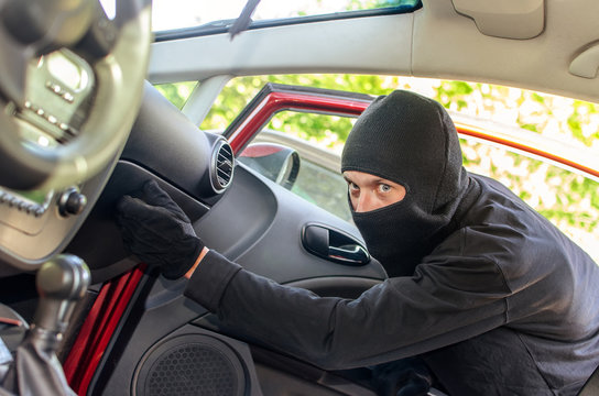 Thief in the mask breaks the door in the car