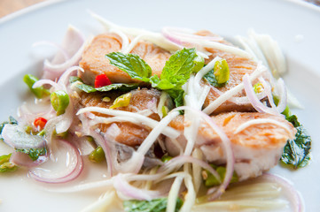 Spicy salad with fried fish and green herb in Thai style