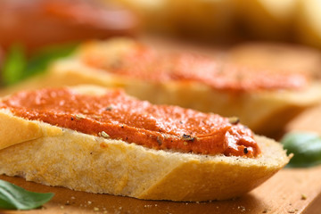 Tomato-butter spread on baguette slices with ground pepper