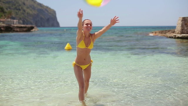Teenage Girl Holding Beach Ball At Beach Wearing Bikini High-Res