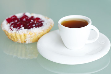 beautiful cake with berries and tea on glass table