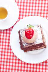 beautiful cake with strawberry and tea on plaid fabric