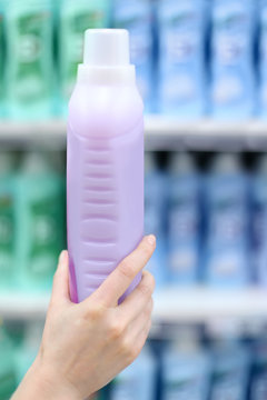 Woman hand holds bottle with abstergent in shop;