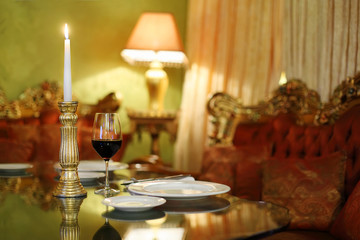 glass with wine and candlestick with candle at table