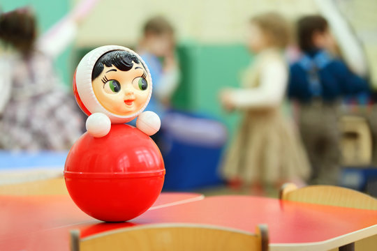 Bright red roly-poly toy stand at table in kindergarten