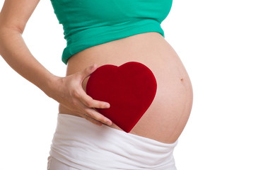 schwangere Frau hält ein Herz in der Hand