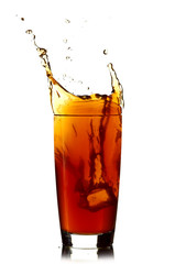 Ice cube droped in cola glass and cola splashing