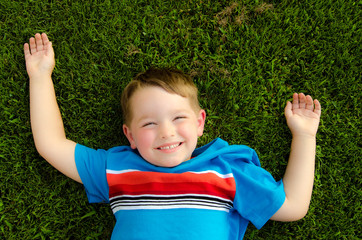 Summer portrait of happy child playing in the grass