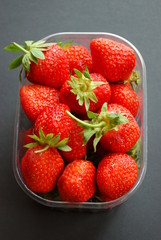 Strawberries in plastic box on dark gray background