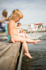 Fototapeta na wymiar Adorable baby sit on pier splash water
