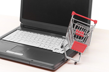 Online shopping. trolley on laptop isolated on white