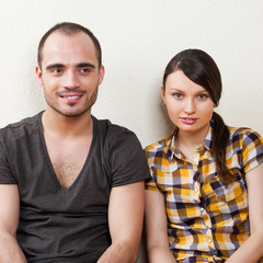 Attractive young adult couple sitting close on floor in home