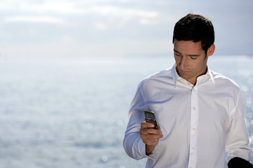Man sending an SMS by the water's edge