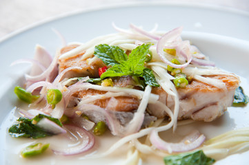 Spicy salad with fried fish and green herb in Thai style