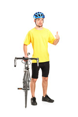 Smiling bicyclist posing next to a bicycle and giving thumb up