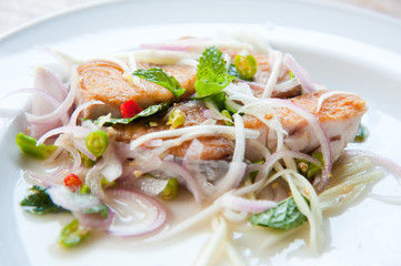 Spicy salad with fried fish and green herb in Thai style