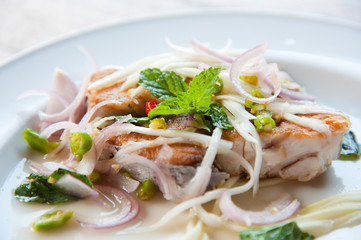 Spicy salad with fried fish and green herb in Thai style