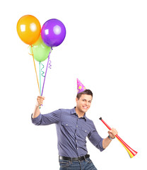 Portrait of a happy male holding balloons and a horn