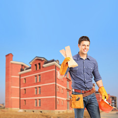 Smiling carpenter holding sills with an apartment block in the b