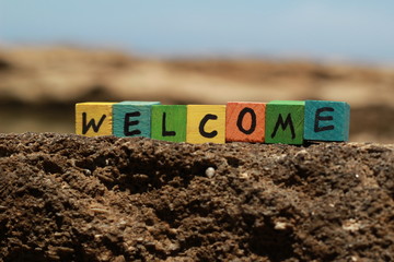 The word Welcome - written on wood cubes, at the beach