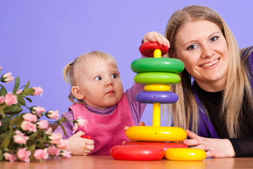 Pretty Caucasian mother with her daughter play with a pyramid