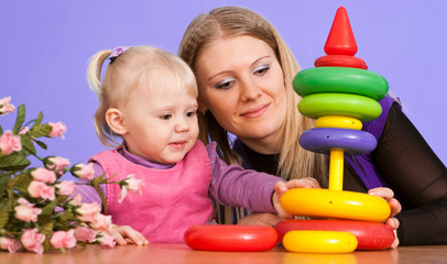 Pretty Caucasian mama with her daughter play with a pyramid
