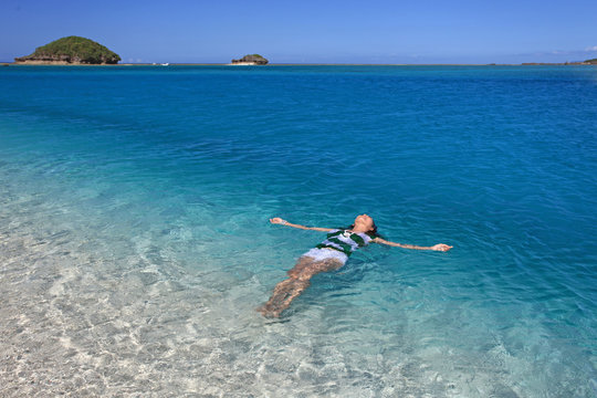 コバルトブルーの美しい海と海水浴を楽しむ女性