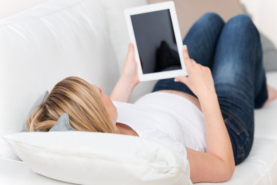 schwangere frau liest am tablet-computer