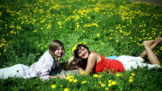 Portrait of mother and daughter lying on meadow and smiling