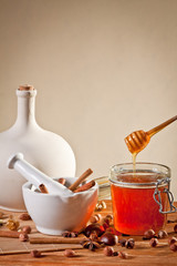 Honey dripping into a jar next to a mortar filled with cinnamon