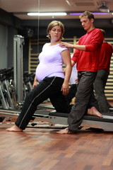 Physical therapist stretching ,pregnant woman's arm in gym