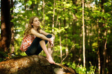 teen girl sitting in a forest daydreaming