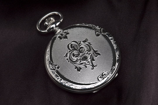 Closed pocket watch on black satin