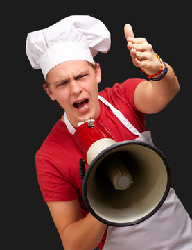 portrait of young cook man screaming with megaphone and gesturin