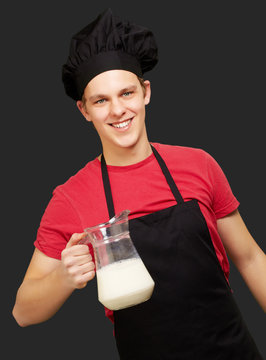 portrait of young cook man holding milk jar over black backgroun