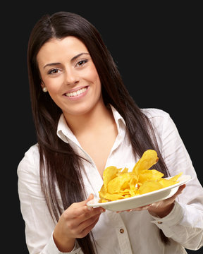 portrait of young woman holding a potato chips plate over black