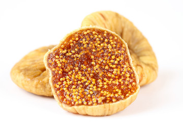 three dried and one cut fig on a white background