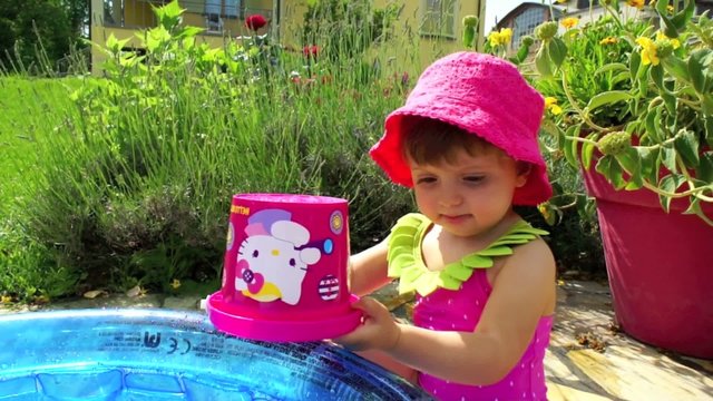 bambina gioca con l'acqua della piscina