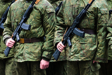 Soldiers stand in formation with weapons