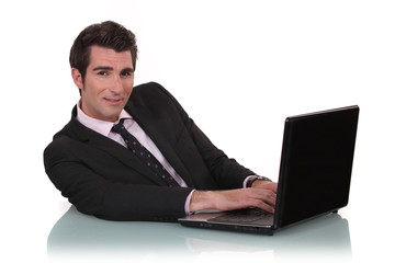 Young business mat sat at desk with laptop