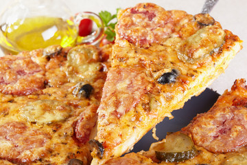 Italian cuisine. Pizza with salami, pickles and olives
