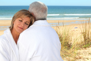 Obraz premium Mature couple in bathrobe on the beach